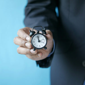 tired but wired and cortisol timing, a hand holding a small alarm clock