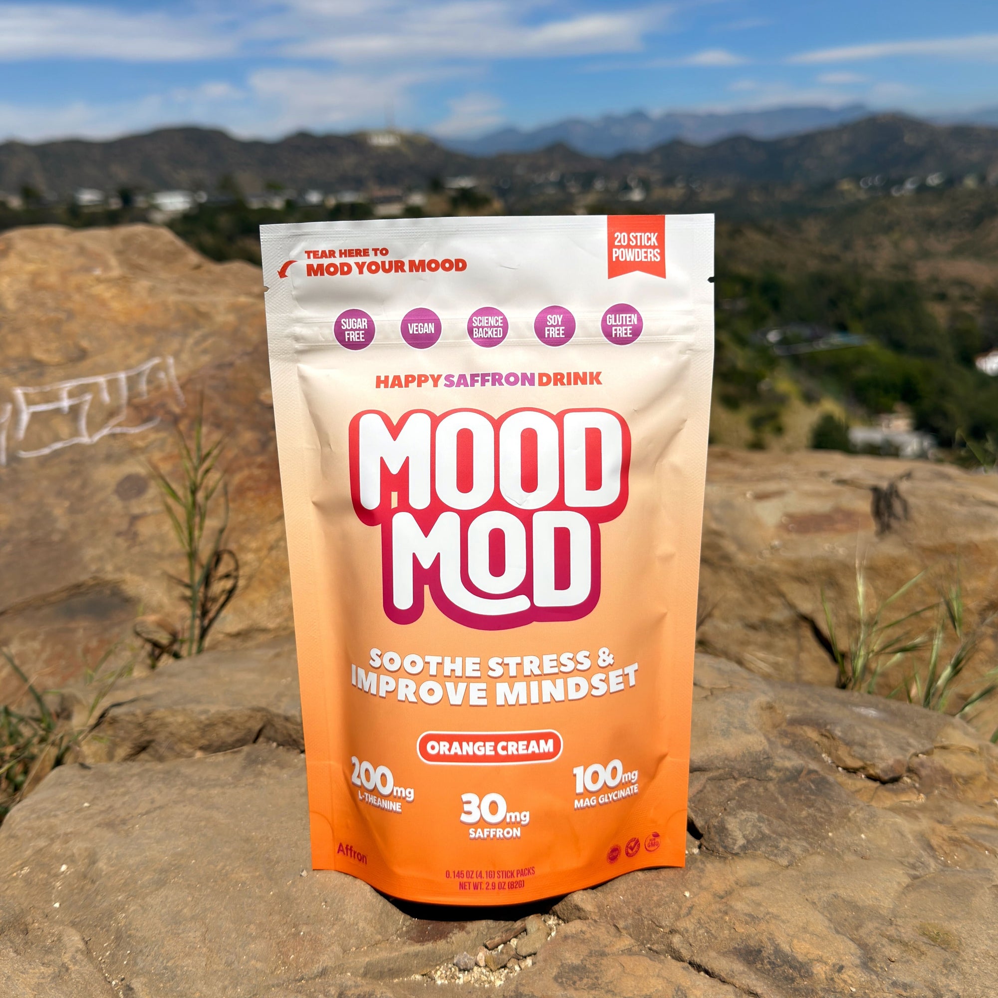 Mood Mod Orange Cream saffron drink stick pouch on a rock with mountains behind.