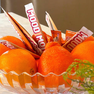Mood Mod and Nello saffron stick packs standing in a bowl of fresh oranges for a mood supplement comparison