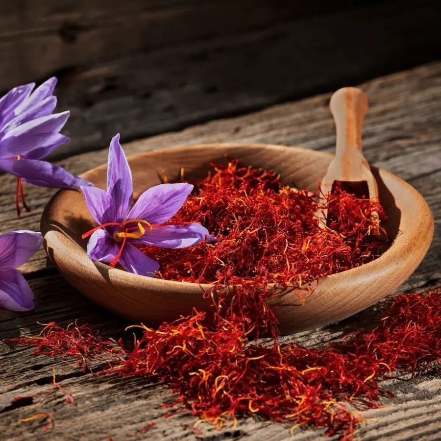 Affron saffron threads in a wooden bowl with purple saffron flowers on a rustic wood table