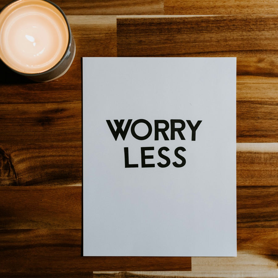 what to drink when stressed or anxious, a calming candle beside a card reading worry less
