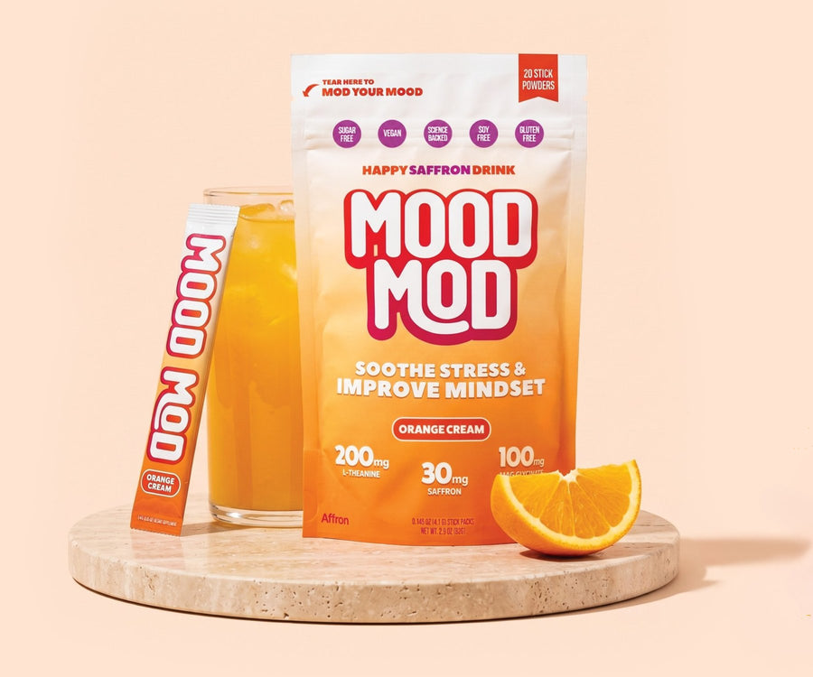 Mood Mod Orange Cream pouch and stick pack beside a glass of the mixed drink